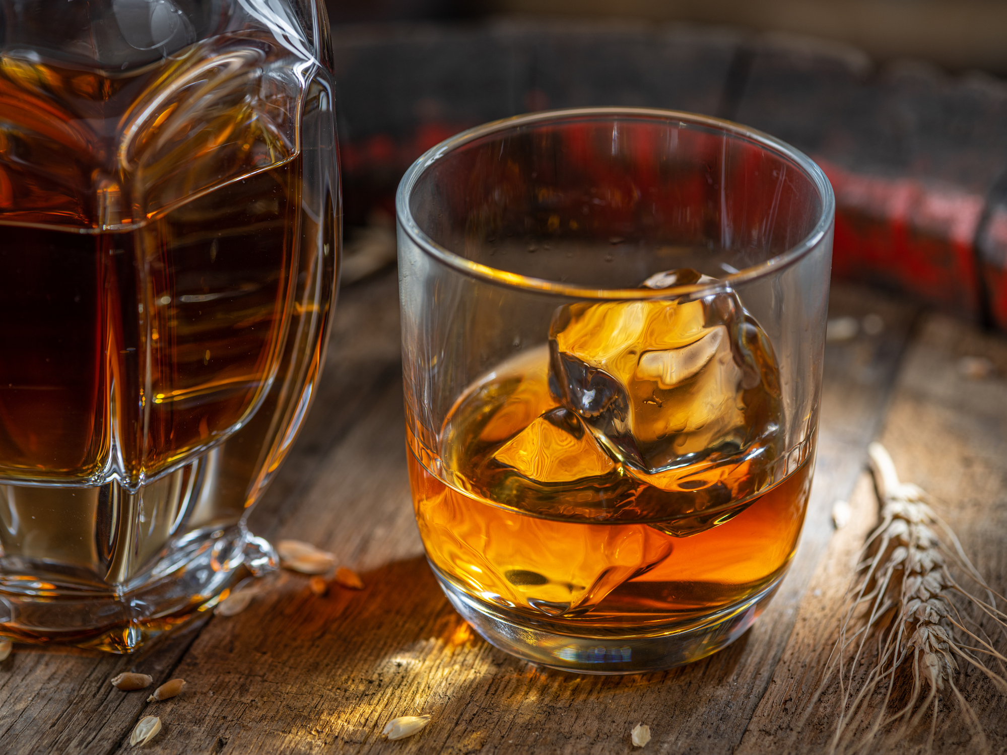 Carafe of whisky and glass of whisky on old wooden cask at the dark background.