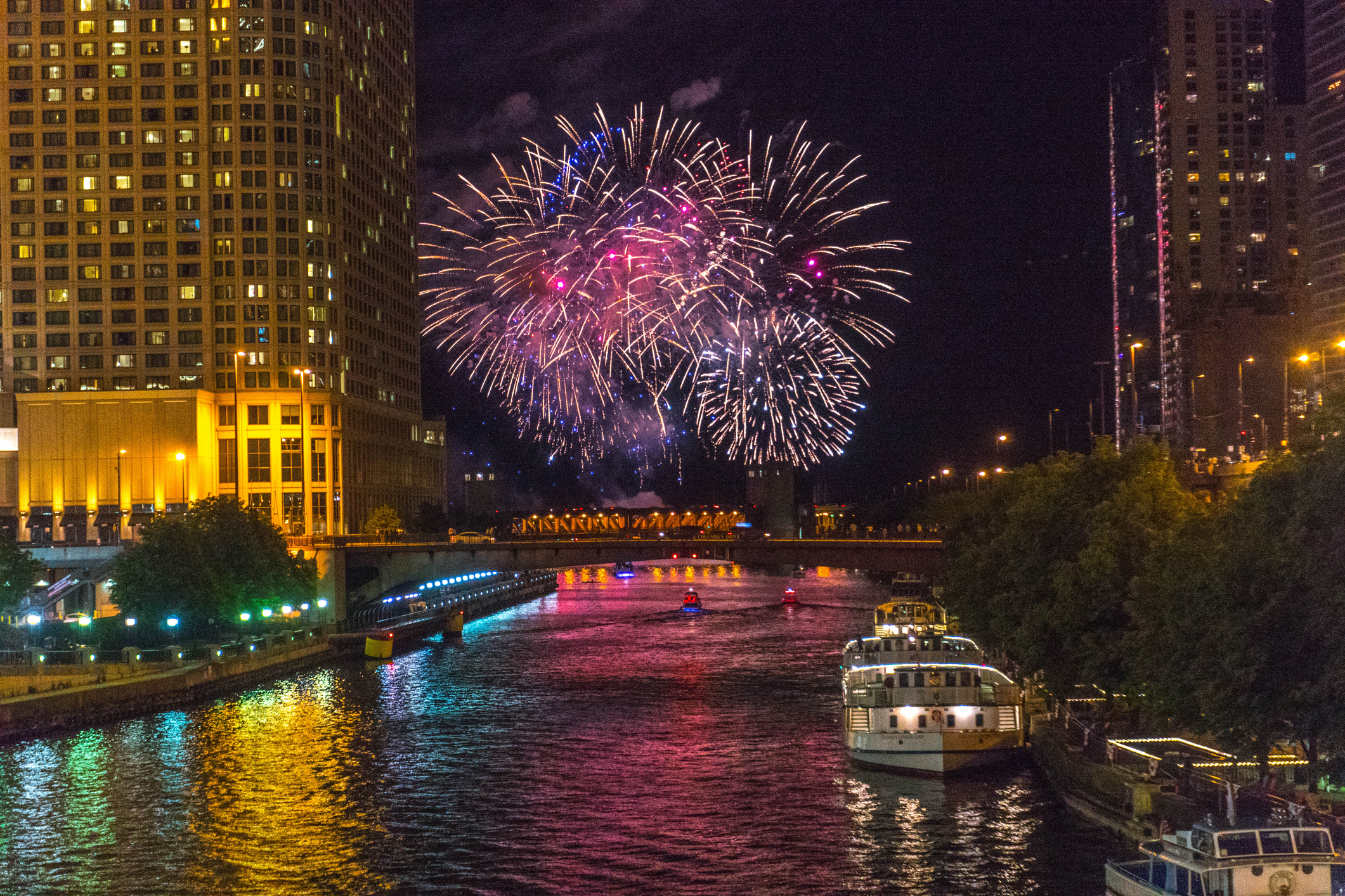 Fireworks exploding over a river.