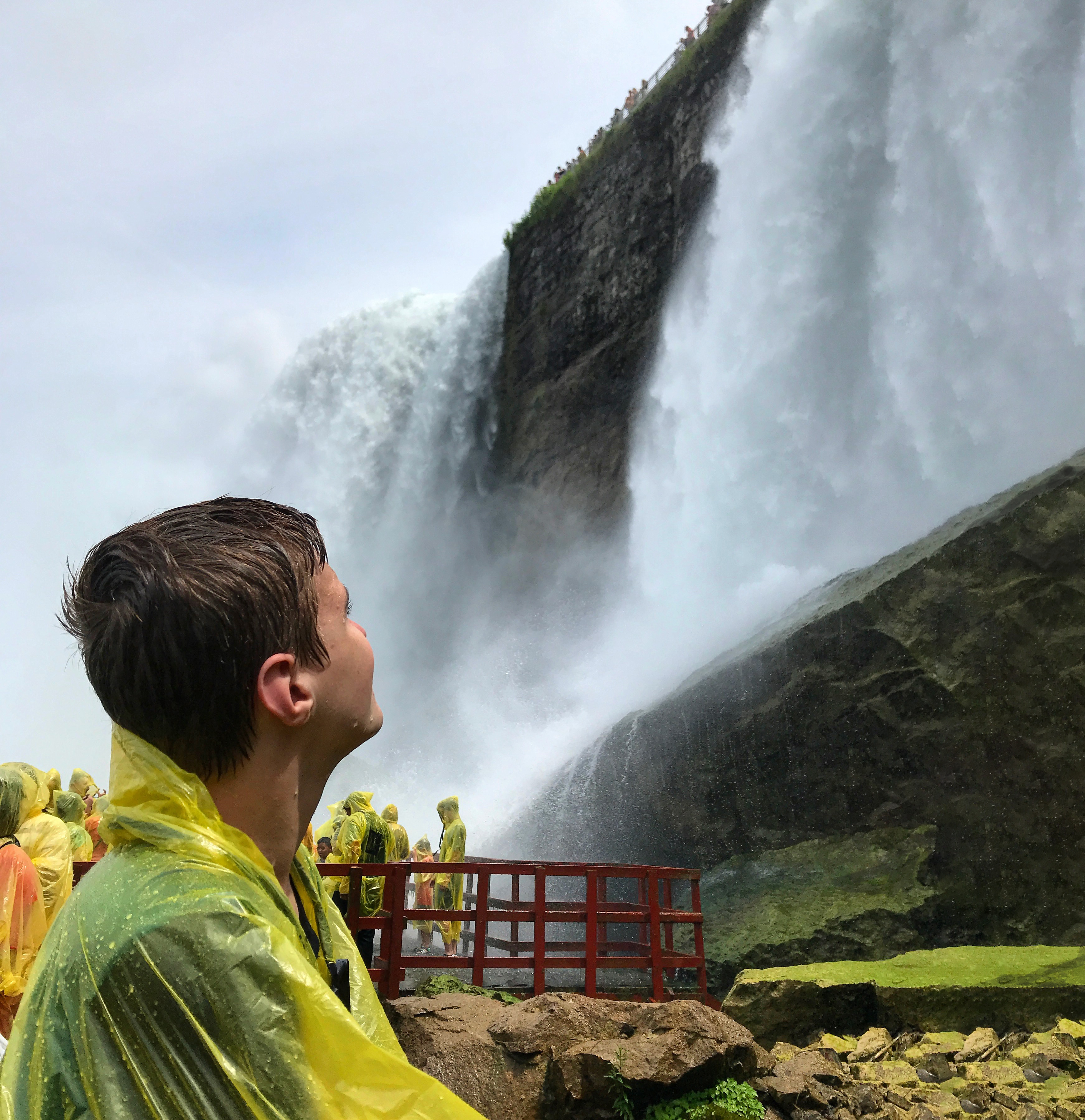 A young man looks up at mammoth waterfalls.