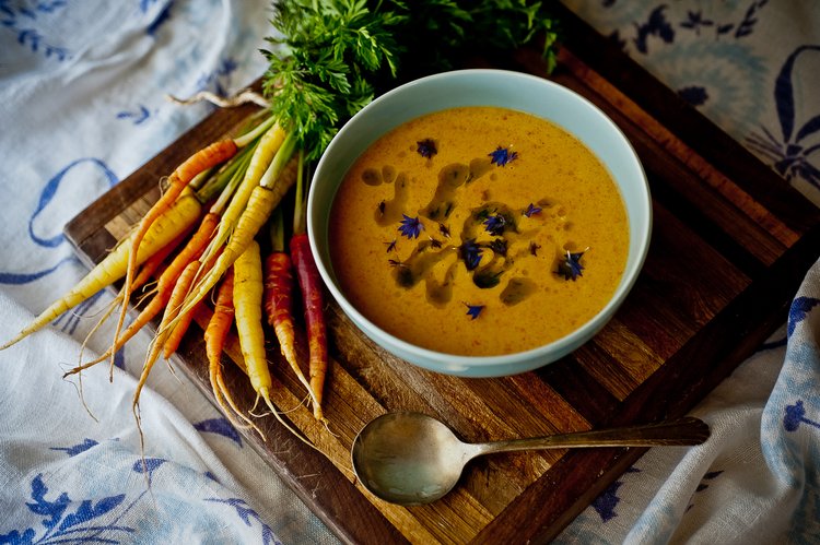 A plate of soup with carrots on the side.