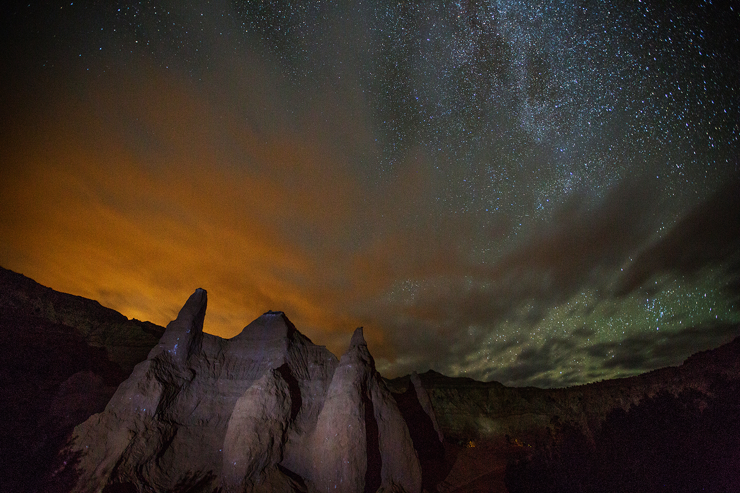 A starry sky hovers over a rock protrusion.