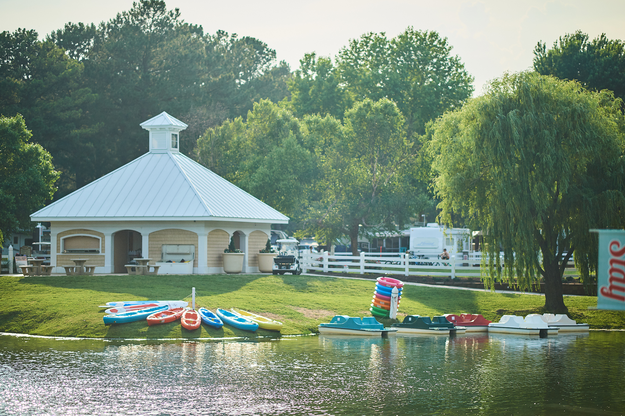 Lake with kayaks sitting on bank.