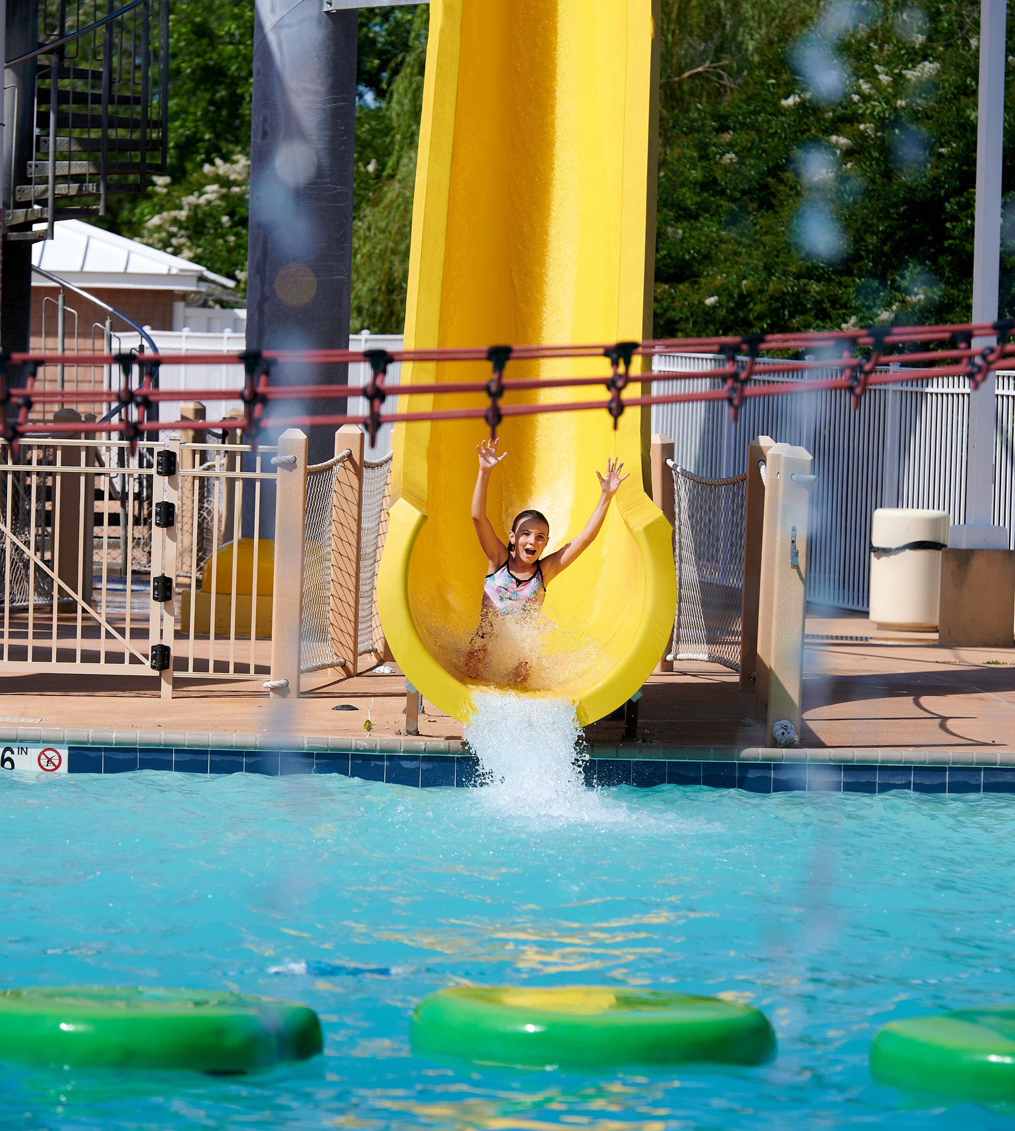 Girl races down a yellow waterslide.