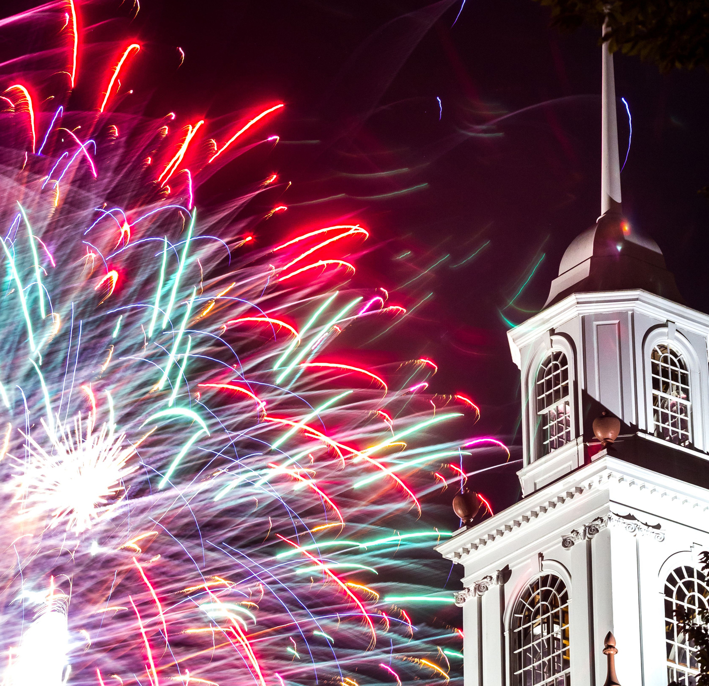 Fireworks illuminate Colonial-era building.