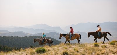 Three horse riders descending a slope.