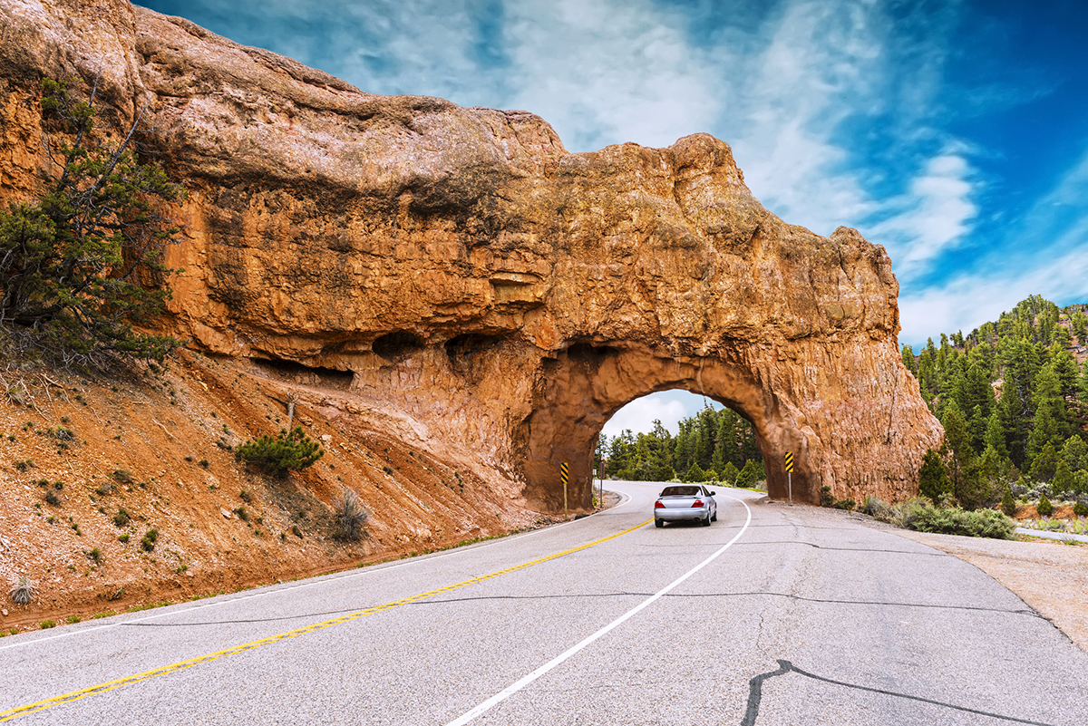Highway snaking under a rock arch.