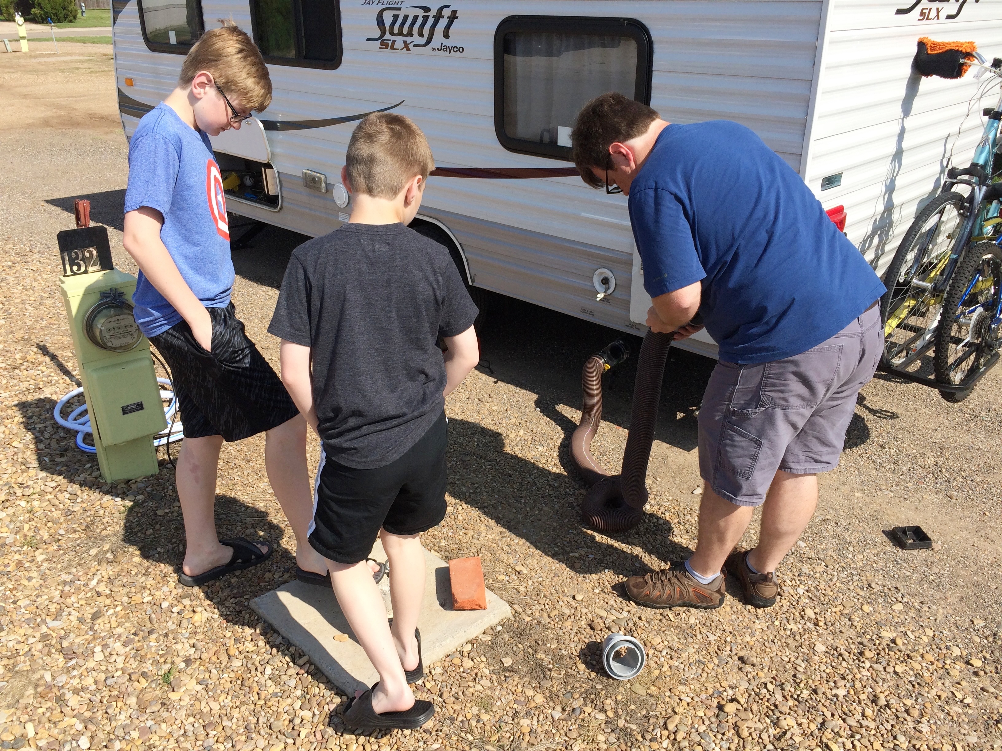 Man and two boys setting up campsite.