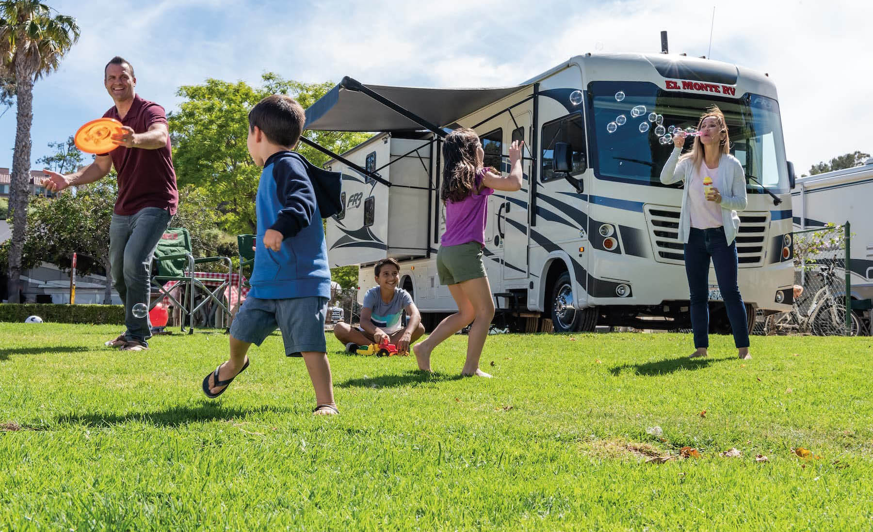 Family playing outside of a Class A motorhome.