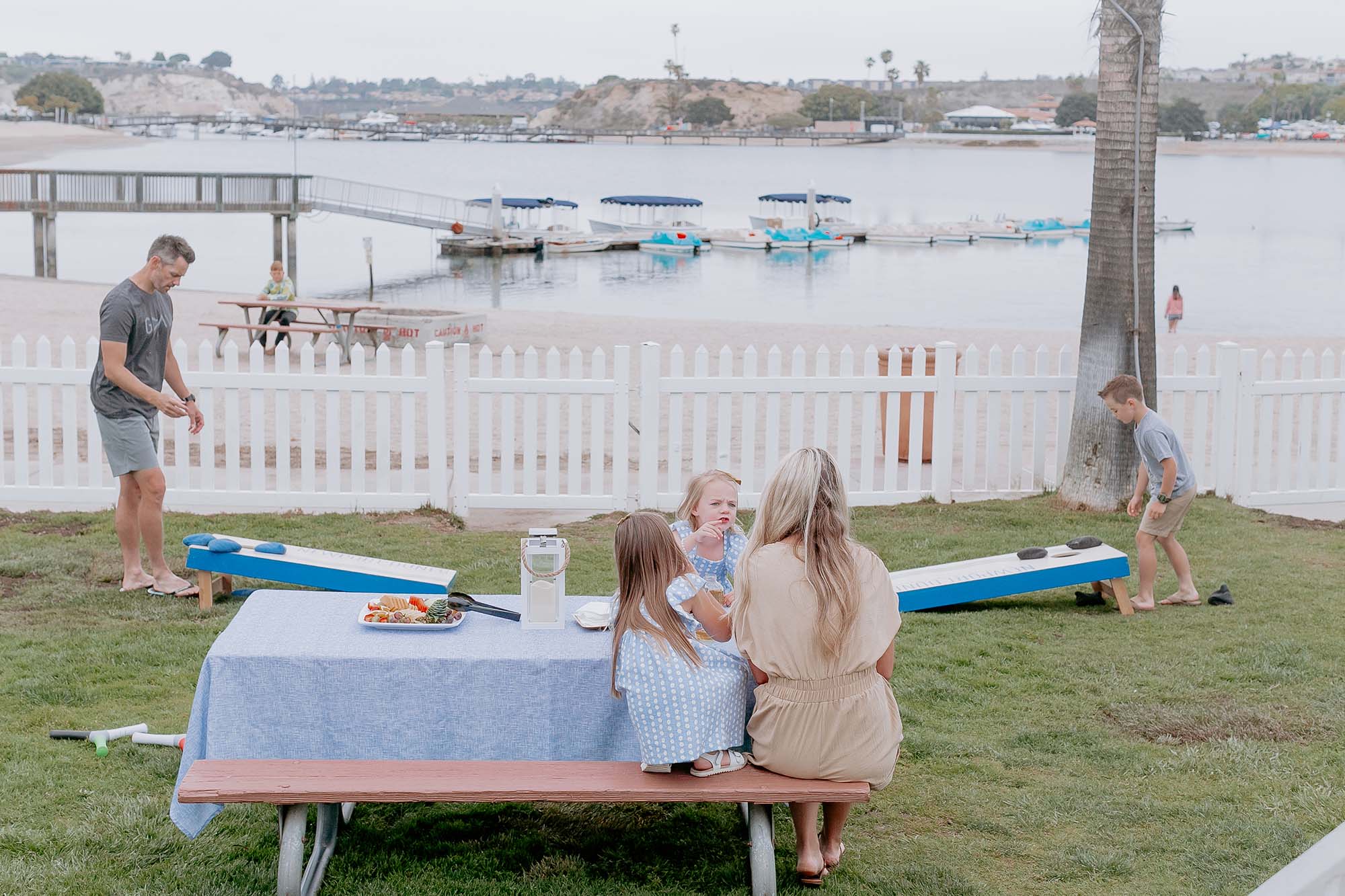 A family playing bean bag outside of cottage.