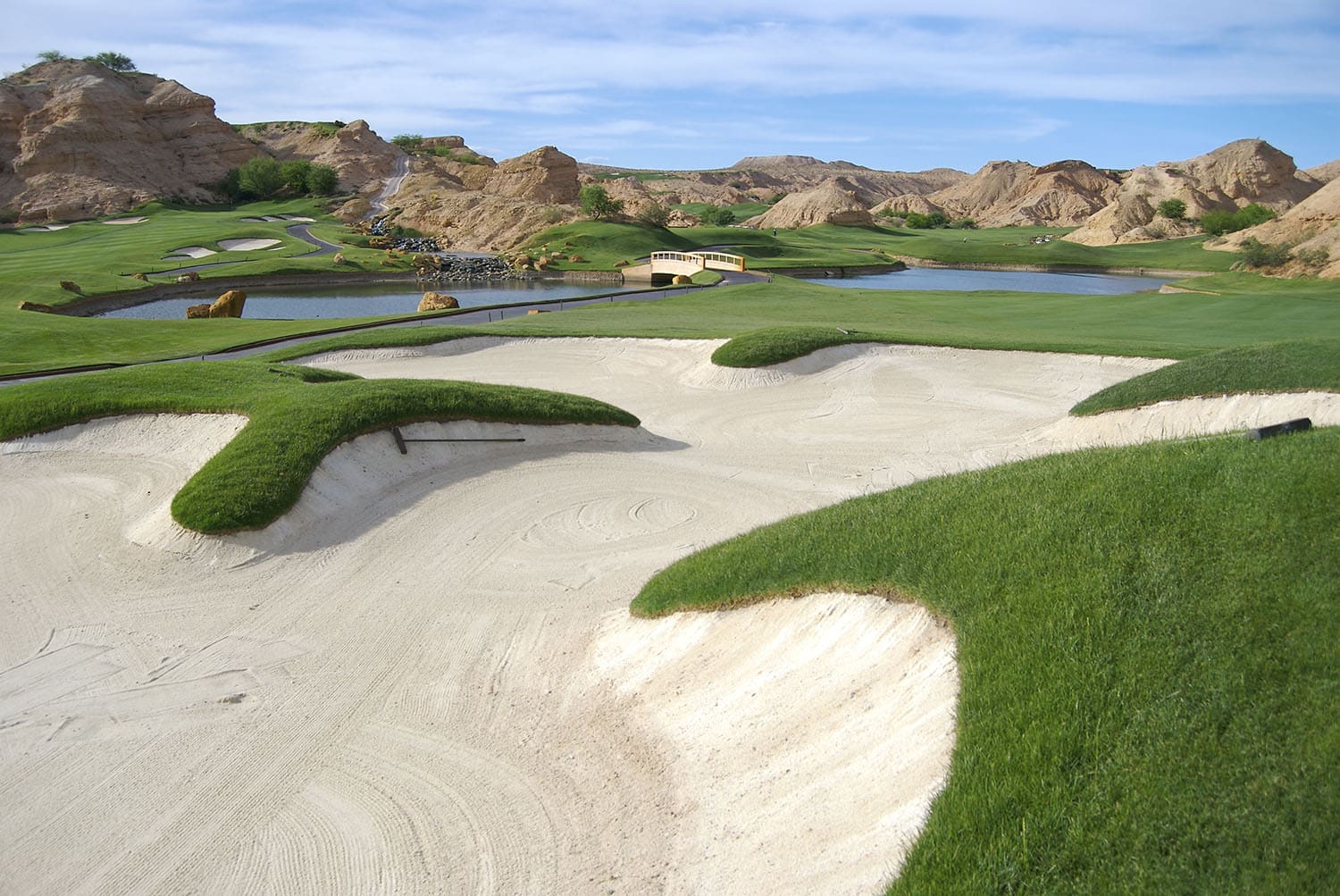 Golf course winding through rocky canyon.