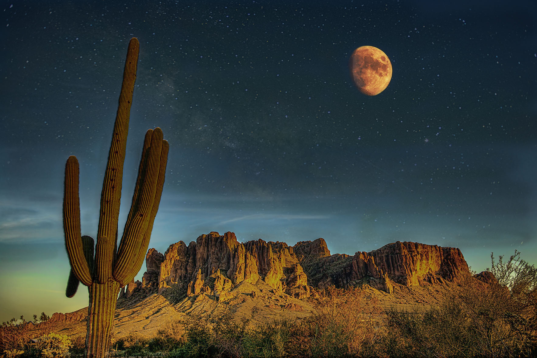 Full moon over a rugged outcropping with cactus in foreground.