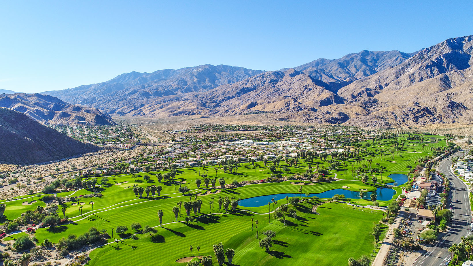 Aerial view of green golf course surrounded by desert hills