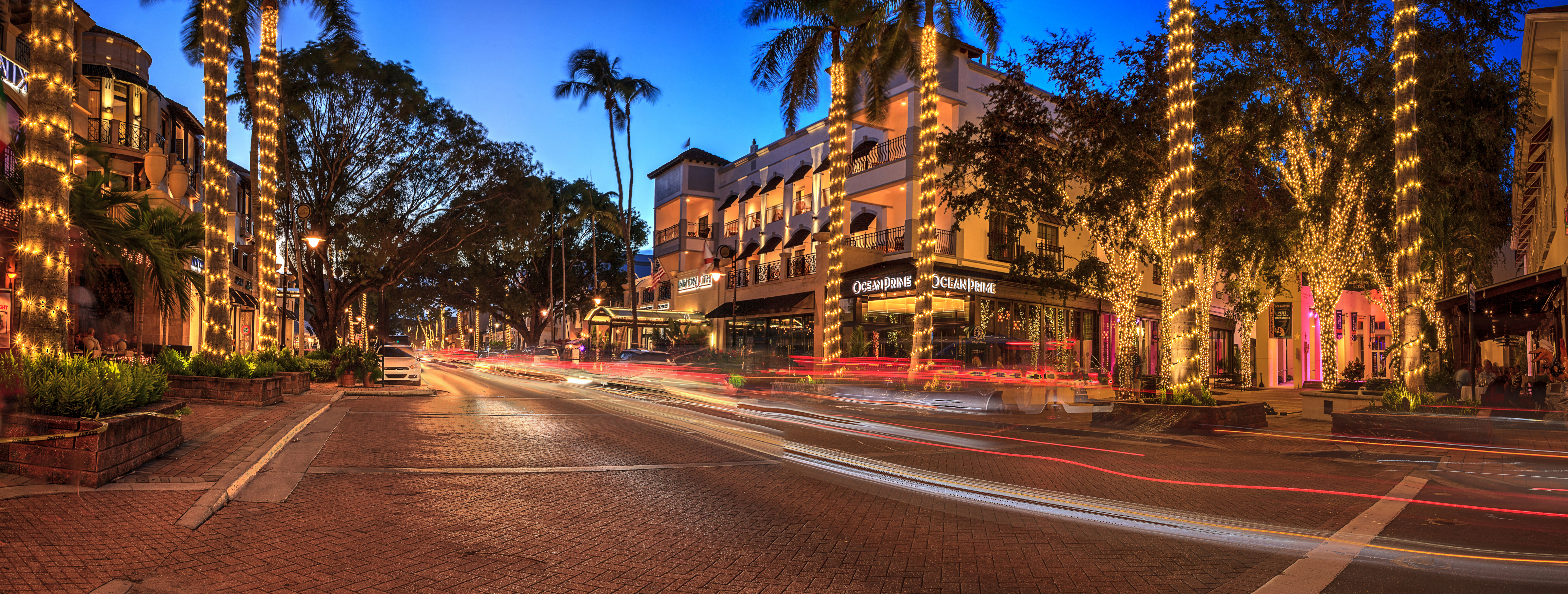 An upscale neighborhood at sunset with palm trees and tony shops.