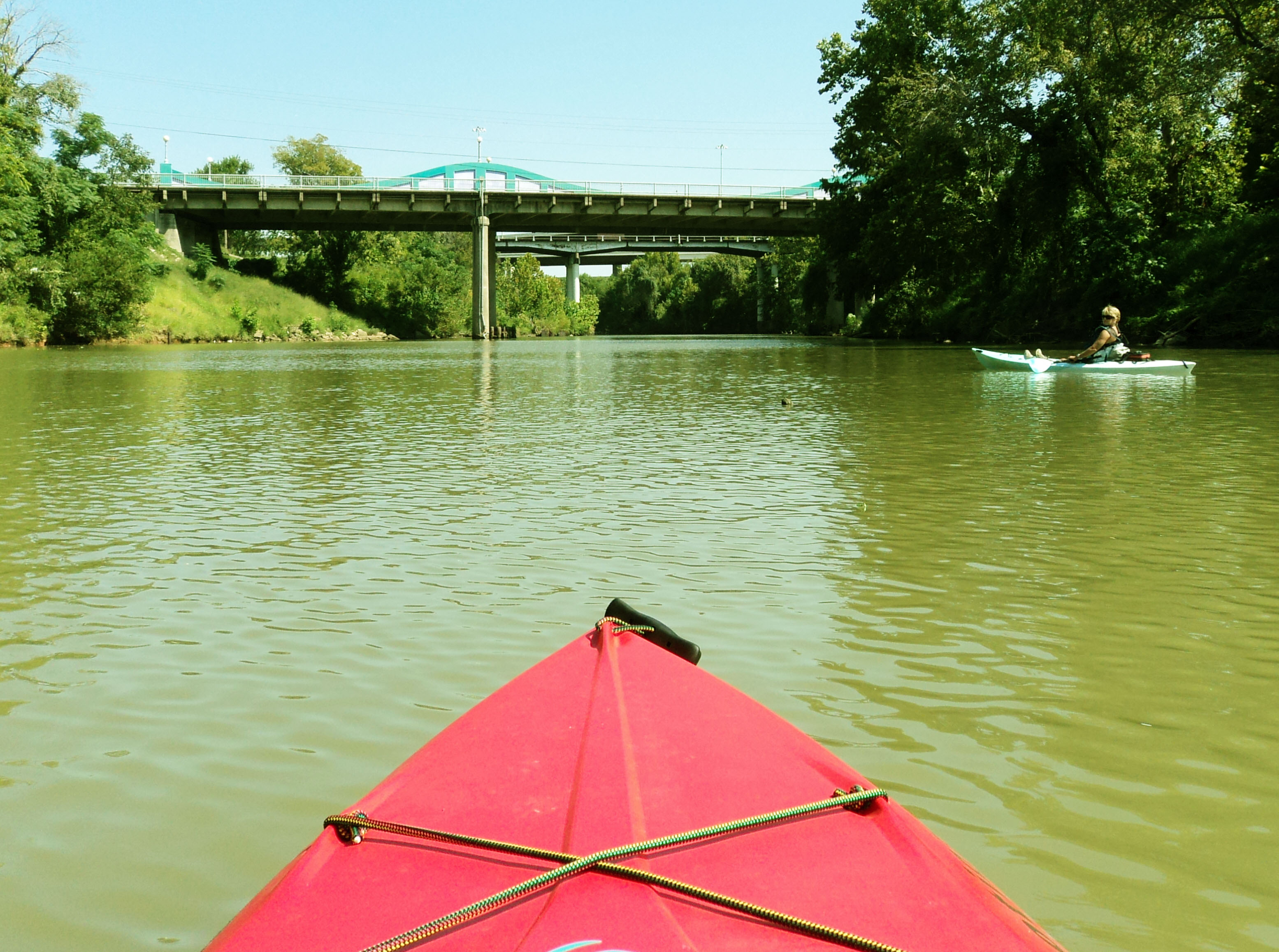 Red kayak paddling through an urban river. 