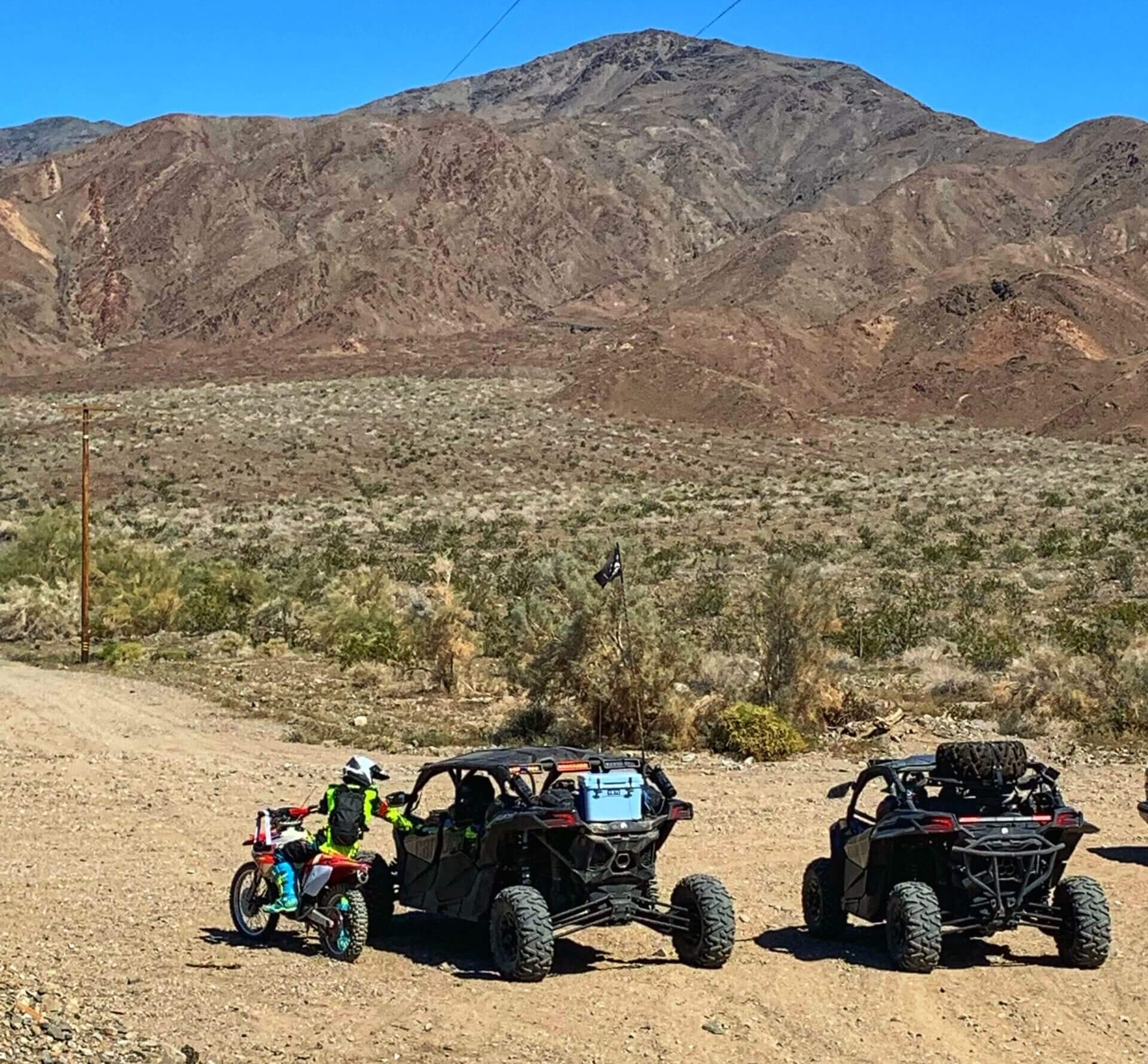 A pair of OHVs and motorcycle on a desert offroading trail.