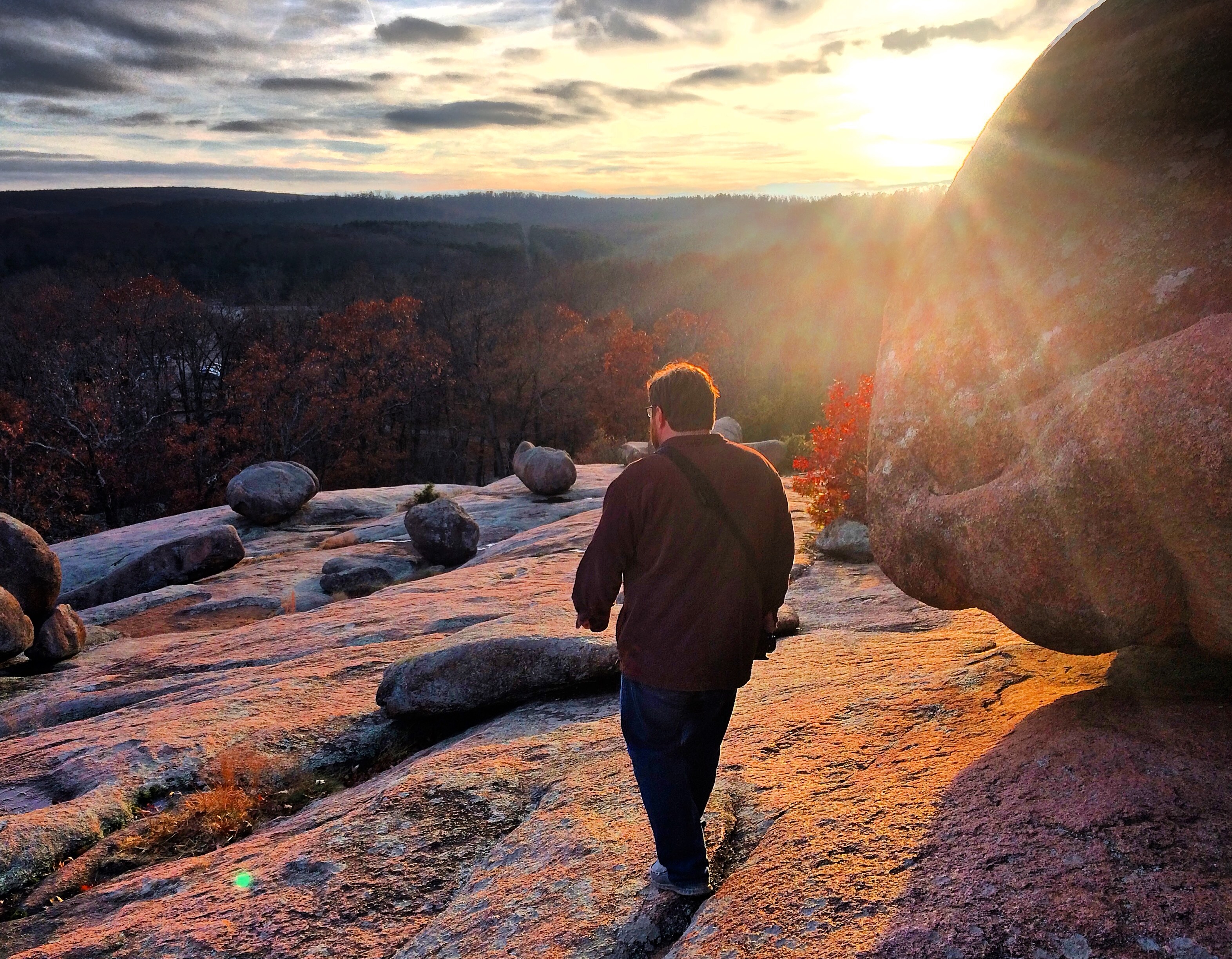 Man walking on rocks at sunset.