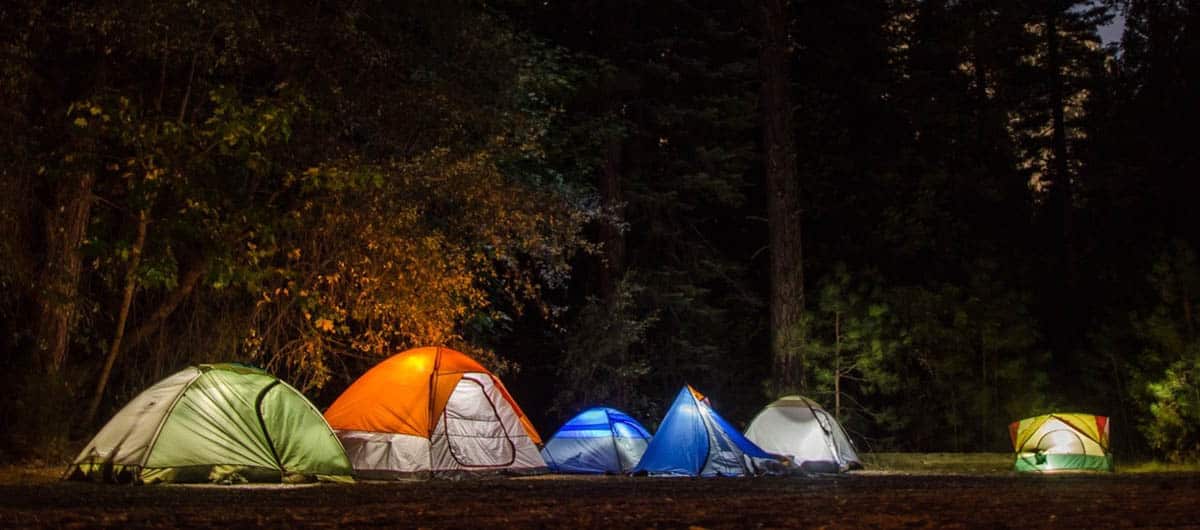 A row of colorful tents list within during a dark night.