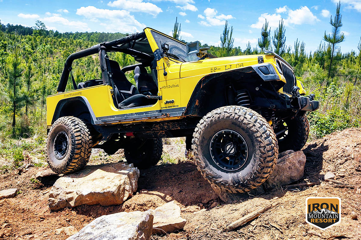 Yellow Jeep ascends a steep, rocky slope.